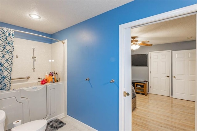 5990 Z Hwy, Edgerton, MO 64444 - bathroom with shower / tub combo with curtain, a textured ceiling, toilet, ceiling fan, and wood finished floors