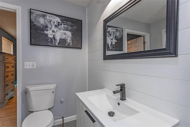 5990 Z Hwy, Edgerton, MO 64444 - half bathroom with vanity, toilet, wooden walls, baseboards, and wood finished floors