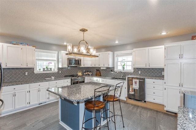 5990 Z Hwy, Edgerton, MO 64444 - kitchen with stainless steel appliances, white cabinets, light stone counters, a kitchen bar, and pendant lighting