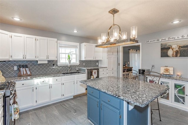 5990 Z Hwy, Edgerton, MO 64444 - kitchen with a sink, blue cabinetry, white cabinets, gas range, and a chandelier