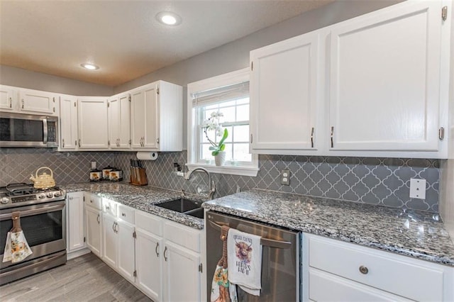 5990 Z Hwy, Edgerton, MO 64444 - kitchen with stainless steel appliances, a sink, dark stone countertops, white cabinetry, and light wood-style flooring