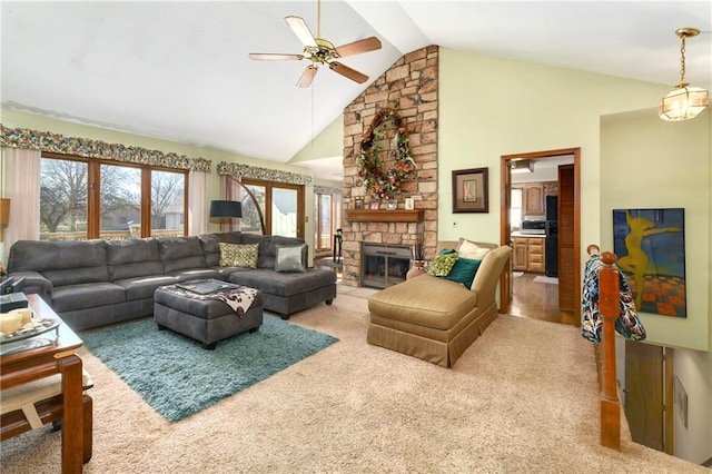 living room featuring high vaulted ceiling, carpet flooring, ceiling fan, and a stone fireplace