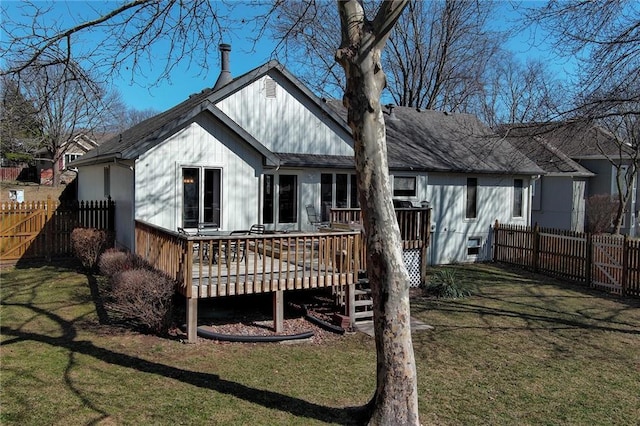 back of house featuring fence, a lawn, and a wooden deck