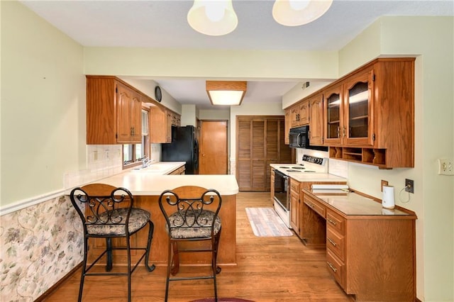 3824 SW Windemere Dr, Lees Summit, MO 64082 - kitchen featuring black appliances, a peninsula, light wood finished floors, and brown cabinetry