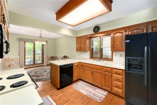 3824 SW Windemere Dr, Lees Summit, MO 64082 - kitchen featuring black appliances, a sink, a peninsula, a chandelier, and light countertops