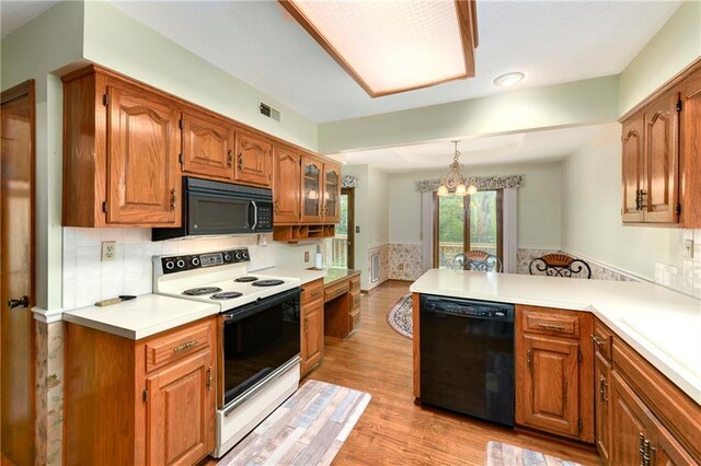 3824 SW Windemere Dr, Lees Summit, MO 64082 - kitchen featuring black appliances, a peninsula, brown cabinetry, and light wood-type flooring