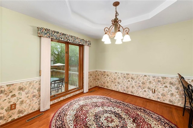 3824 SW Windemere Dr, Lees Summit, MO 64082 - dining space with wood finished floors, a chandelier, wallpapered walls, a raised ceiling, and wainscoting