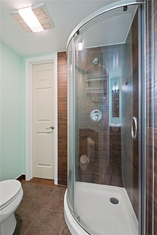 bathroom with a stall shower, tile patterned flooring, and toilet