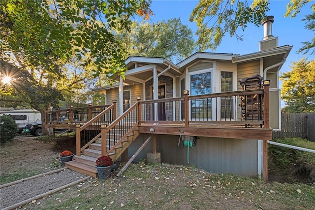 back of house featuring stairs, a deck, a chimney, and fence