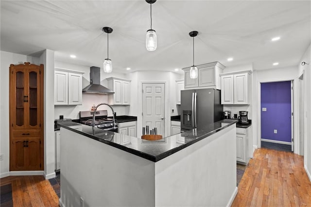 kitchen with appliances with stainless steel finishes, recessed lighting, wall chimney range hood, and hardwood / wood-style flooring