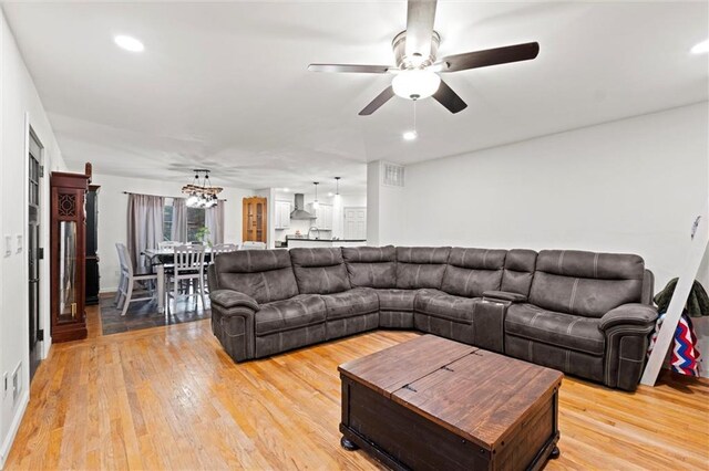 living area featuring ceiling fan with notable chandelier, light wood finished floors, and recessed lighting