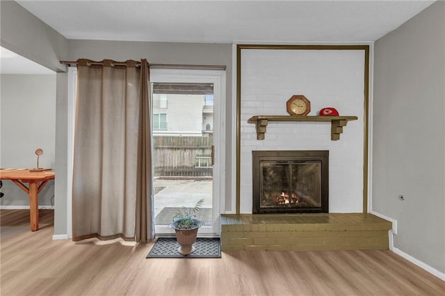 living area with a fireplace, wood finished floors, and baseboards