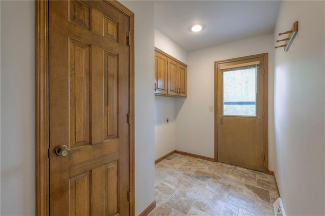 laundry area featuring cabinet space, baseboards, hookup for an electric dryer, and stone finish floor