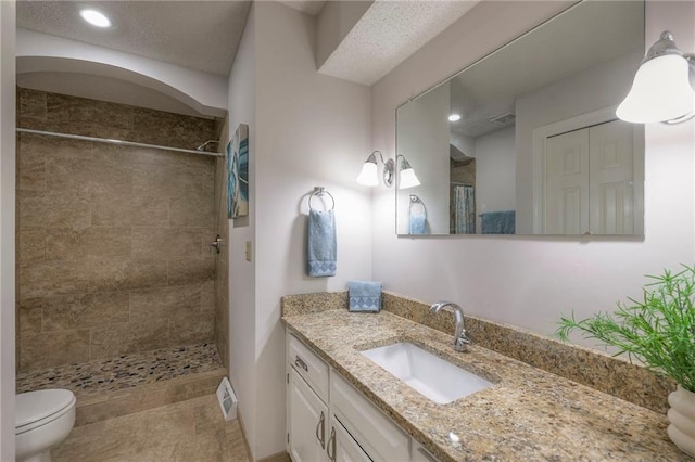 bathroom with vanity, toilet, recessed lighting, visible vents, and tiled shower