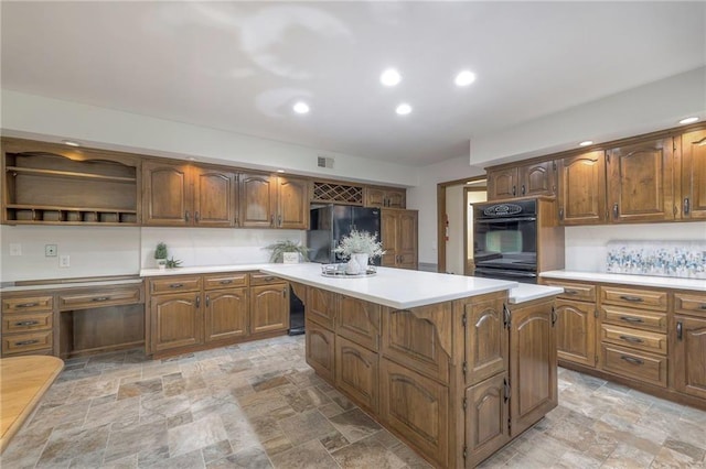 12016 Ballentine St, Overland Park, KS 66213 - kitchen featuring black appliances, light countertops, light stone finish flooring, a center island, and brown cabinets