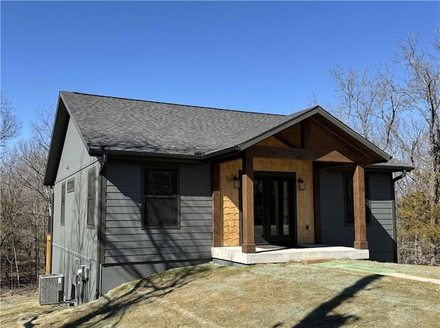 view of front of home featuring central AC and roof with shingles