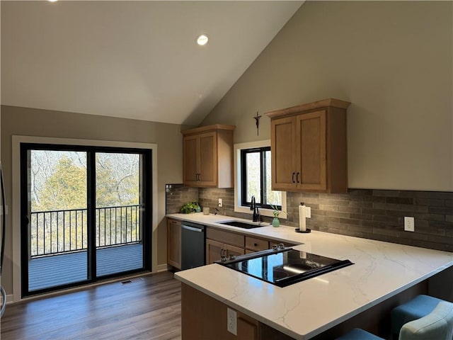 kitchen with a sink, light wood-style floors, a peninsula, cooktop, and dishwashing machine