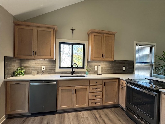 kitchen featuring a sink, stainless steel appliances, lofted ceiling, and light countertops