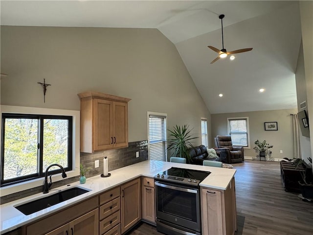 kitchen featuring stainless steel electric range oven, a peninsula, a sink, light countertops, and open floor plan