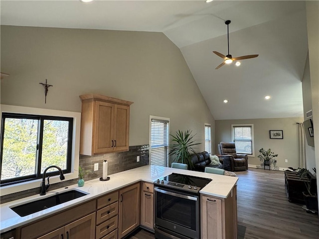 kitchen featuring a sink, open floor plan, electric range oven, a peninsula, and light countertops