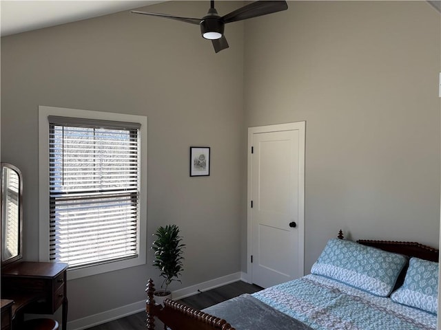 bedroom featuring dark wood-style floors, multiple windows, a high ceiling, and baseboards