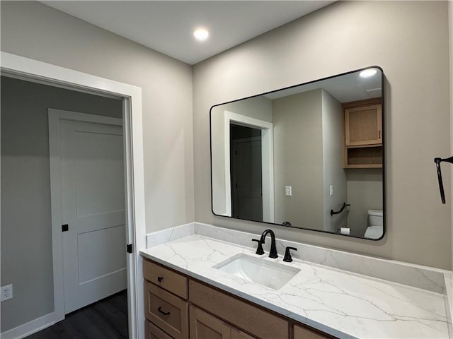 bathroom with recessed lighting, toilet, wood finished floors, and vanity