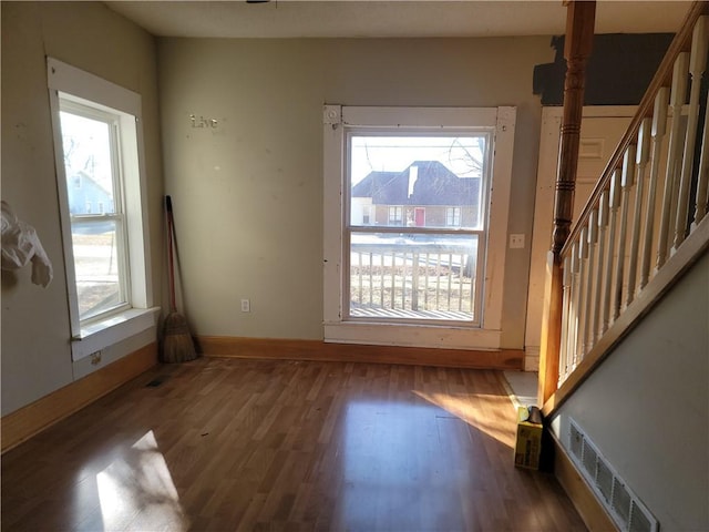 doorway to outside with wood finished floors, visible vents, plenty of natural light, and stairs