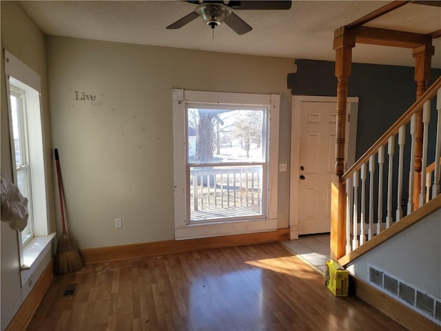 entryway featuring baseboards, visible vents, a ceiling fan, wood finished floors, and stairs