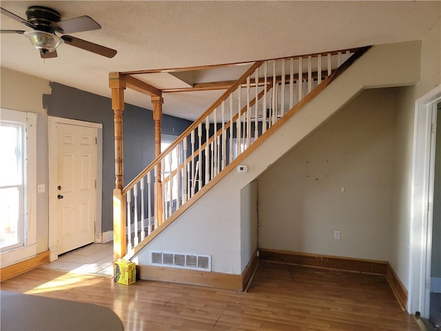 stairs featuring a wealth of natural light, wood finished floors, visible vents, and baseboards