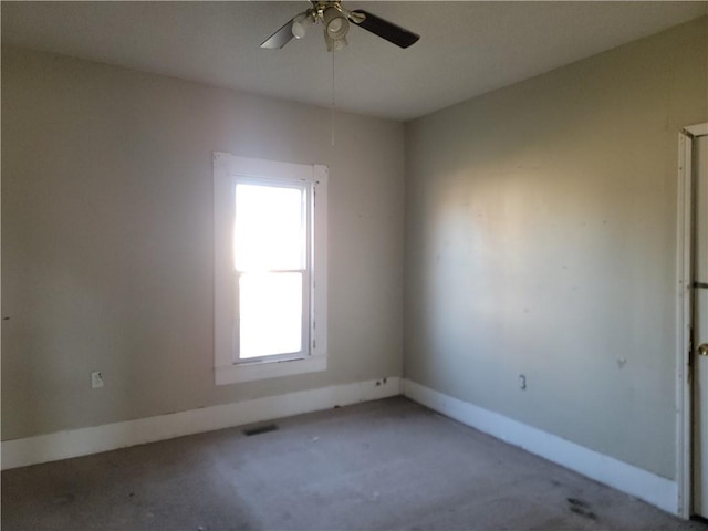 spare room with ceiling fan, visible vents, and baseboards