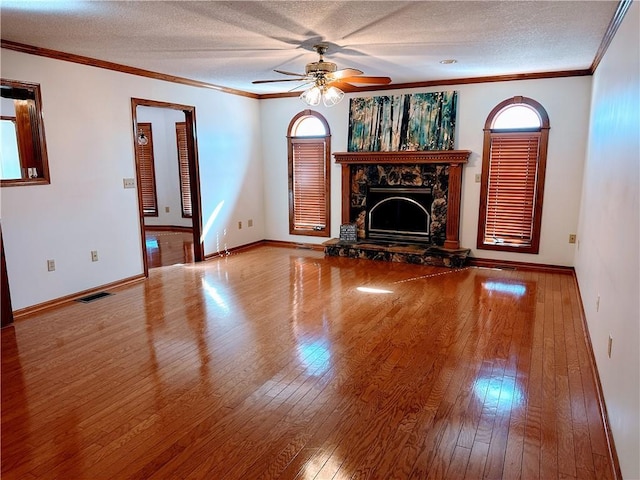 unfurnished living room featuring ornamental molding, a stone fireplace, hardwood / wood-style flooring, and visible vents