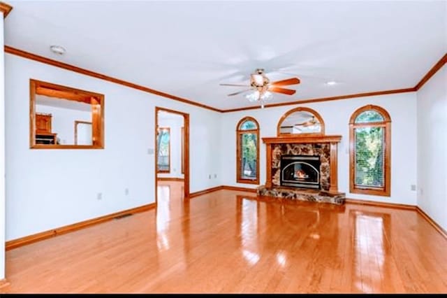 unfurnished living room with ceiling fan, a fireplace, baseboards, and wood finished floors