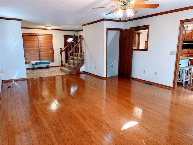 unfurnished living room with stairway, wood-type flooring, visible vents, and crown molding