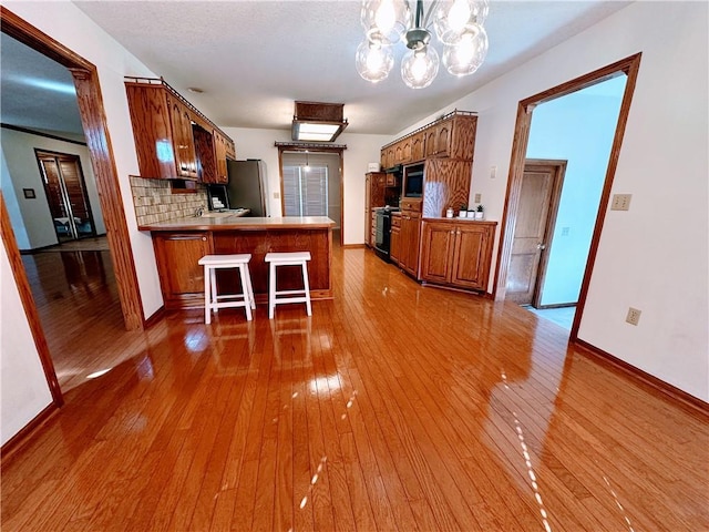 kitchen featuring hardwood / wood-style flooring, freestanding refrigerator, and brown cabinets