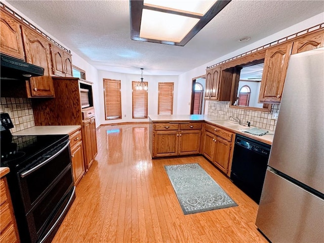 kitchen featuring black appliances, light wood finished floors, a sink, and brown cabinets