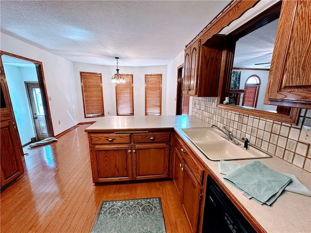 kitchen featuring light wood-style floors, light countertops, a sink, and a peninsula