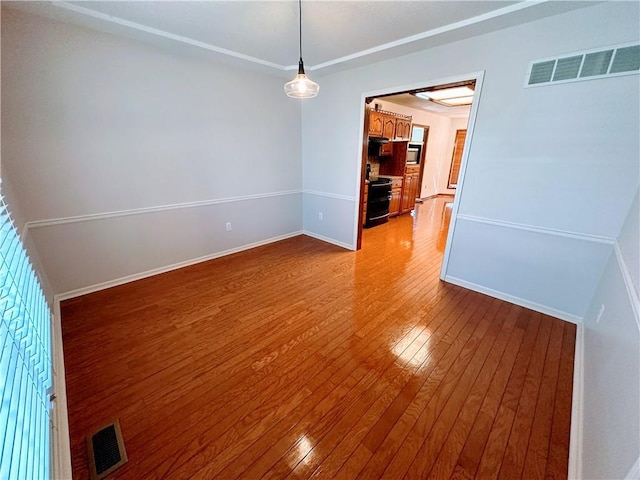 spare room featuring baseboards, visible vents, and hardwood / wood-style floors