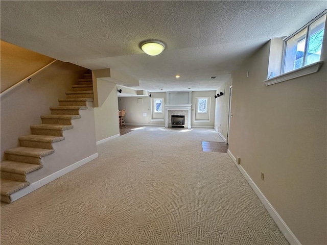 unfurnished living room with stairway, carpet, a fireplace, and baseboards