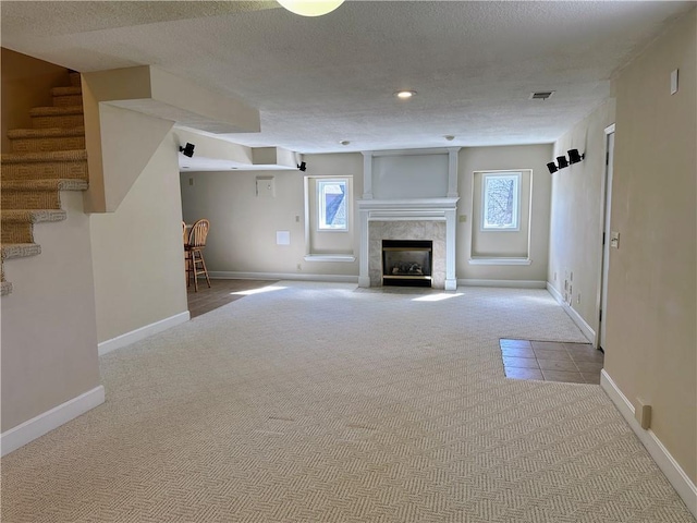 unfurnished living room featuring carpet floors, a wealth of natural light, baseboards, and stairs