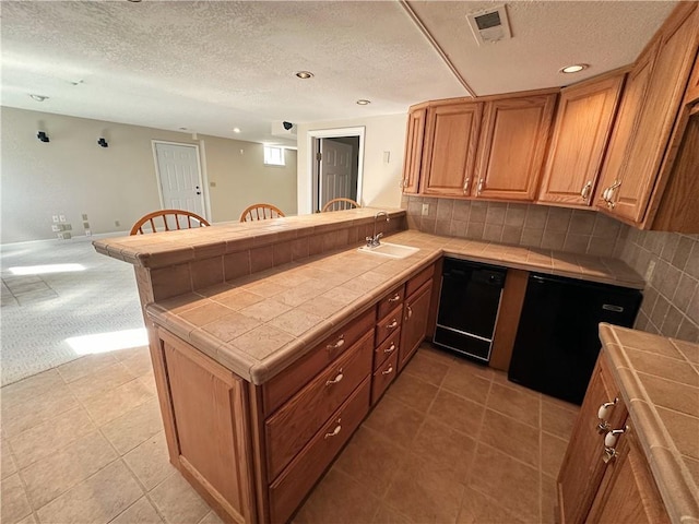 kitchen with tile countertops, a peninsula, black dishwasher, and a sink