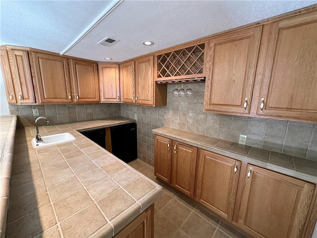 kitchen with visible vents, tile counters, decorative backsplash, and a sink