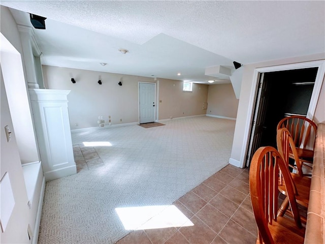 interior space featuring carpet flooring, a textured ceiling, baseboards, and tile patterned floors