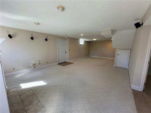 empty room featuring carpet flooring, a textured ceiling, and baseboards