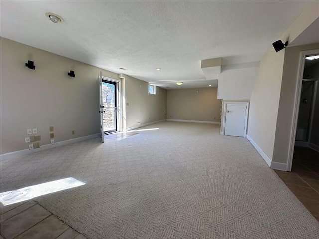 spare room with carpet flooring, a textured ceiling, and baseboards