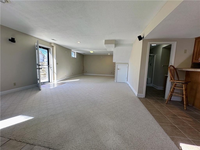 carpeted empty room featuring tile patterned flooring, baseboards, and a textured ceiling