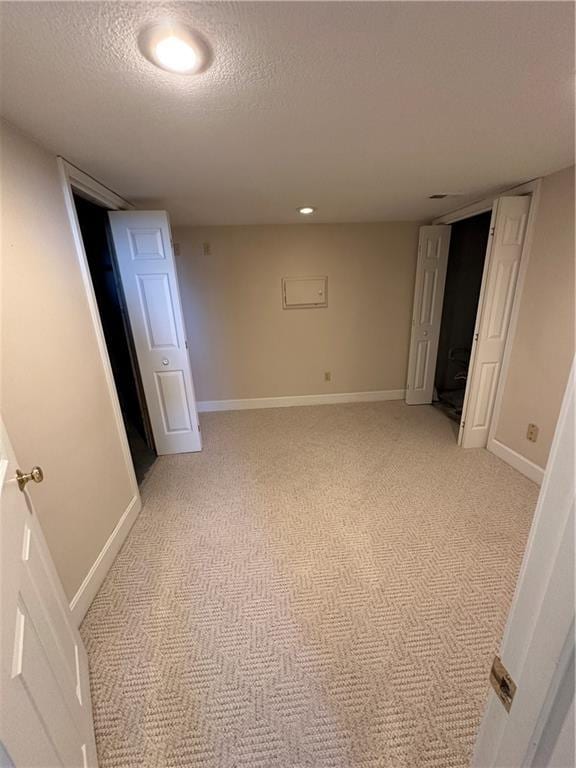 interior space with light carpet, baseboards, a textured ceiling, and recessed lighting