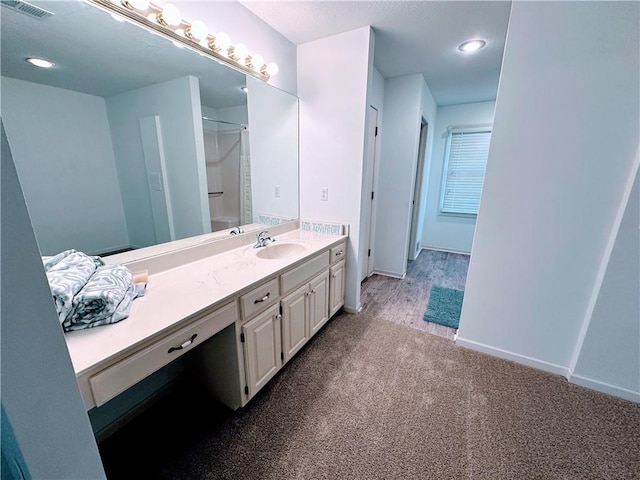 bathroom with visible vents, baseboards, walk in shower, carpet flooring, and vanity