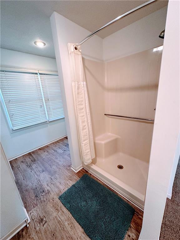 bathroom with a stall shower, baseboards, and wood finished floors