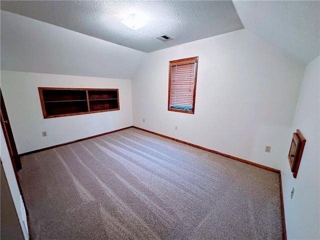 bonus room featuring a textured ceiling, built in shelves, vaulted ceiling, and baseboards