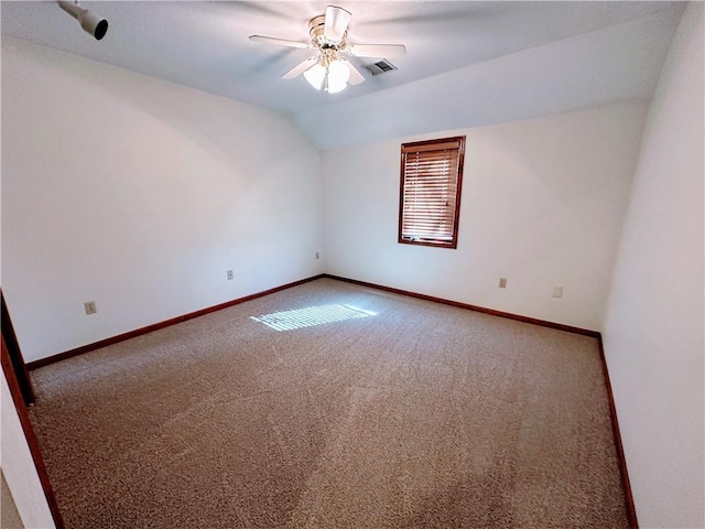 carpeted spare room with lofted ceiling, ceiling fan, visible vents, and baseboards